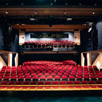 Vista dal palcoscenico delle file di sedili rossi e dell'illuminotecnica nel moderno auditorium del Teatro TAK Liechtenstein