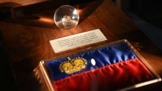 Mostra nella Camera del Tesoro del Liechtenstein: bandiera del Liechtenstein con corona d'oro e globo di vetro con manufatto storico