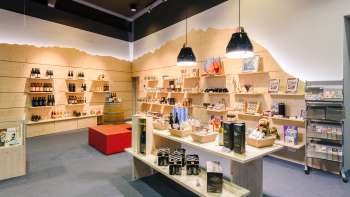 Luminoso centro visitatori con moderni scaffali in legno pieni di souvenir, specialità e materiale informativo. Luminoso centro visitatori con moderni scaffali in legno pieni di souvenir, specialità e materiale informativo.