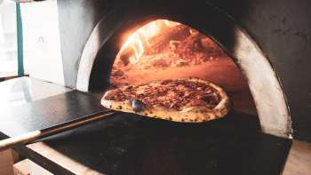 Pizza in forno a legna con crosta dorata e croccante