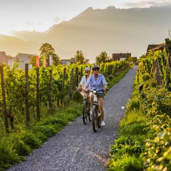 Due ciclisti nei vigneti del Liechtenstein al tramonto - tour in e-bike con vista sulle Alpi e sulle vigne