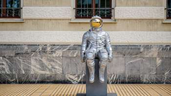 Scultura di astronauta in argento "Raumableiter" di Max Grüter davanti al palazzo del governo di Vaduz - arte moderna nello spazio pubblico.