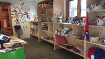 Interno della Birkahoflädile con scaffali in legno pieni di prodotti regionali, decorati con elementi colorati - negozio di fattoria in Liechtenstein.