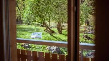 Vista dal balcone della guest house del campeggio Mittagsspitze sul verde con alberi e prato per prendere il sole.