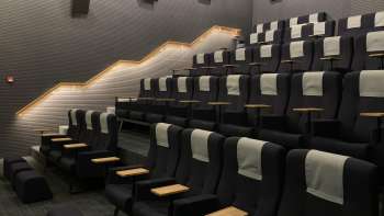 Moderna sala cinematografica nello Skino Schaan con comode poltrone, tavolini e illuminazione soffusa.