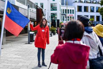 La guida cittadina presenta la bandiera del Liechtenstein durante una visita guidata nel centro di Vaduz