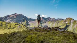 Escursionista su una vetta del Liechtenstein con vista su un'imponente catena montuosa - estate, libertà e natura pura