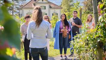 Visita guidata della cantina dove una donna informa il gruppo sul vino e sulla cultura in mezzo alle vigne.