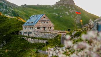 Primo piano del rifugio Pfälzerhütte con la bandiera del Liechtenstein di sera.