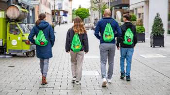 Quattro giovani con lo zaino verde FoodTrail passeggiano nel centro di Vaduz