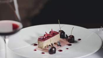 Elegante dessert su un piatto bianco, decorato con ciliegie e cioccolato
