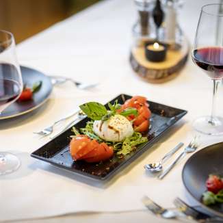 Insalata di pomodori freschi e mozzarella con vino rosso su una tavola imbandita al JUFA Hotel Malbun