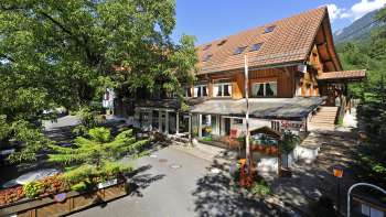 Vista esterna dell'edificio principale del campeggio Mittagsspitze con ristorante e terrazza ombreggiata.