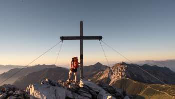 Escursionista presso la croce di vetta sul monte Augstenberg