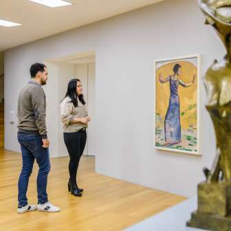 Una coppia osserva i dipinti nella luminosa galleria del museo d’arte del Liechtenstein, con sculture moderne in primo piano.