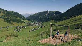 Una famiglia si diverte a dondolare insieme sul sentiero delle altalene a Malbun