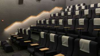 Moderna sala cinematografica nello Skino Schaan con comode poltrone, tavolini e illuminazione soffusa.