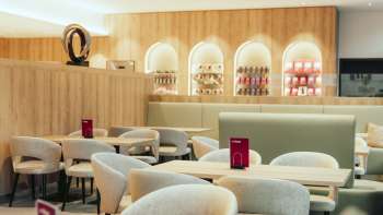 Moderna caffetteria con elementi in legno chiaro, aree di seduta eleganti e un'atmosfera invitante.