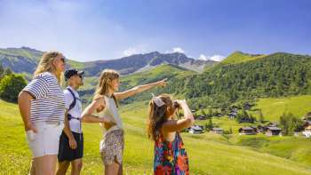 Famiglia che guarda in lontananza nel paesaggio alpino con vista sulle montagne in estate Famiglia che guarda in lontananza nel paesaggio alpino con vista sulle montagne in estate