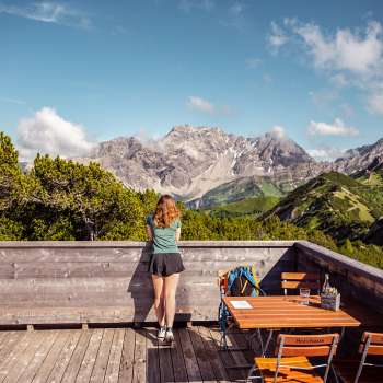 L'escursionista si affaccia dalla terrazza in legno della piattaforma panoramica su un impressionante panorama alpino.