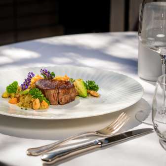Piatto di carne squisitamente preparato con verdure e fiori sulla terrazza del Park Hotel Sonnenhof a Vaduz, Liechtenstein