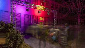 Ingresso del Kleintheater Schlösslekeller di notte con illuminazione colorata e pubblico