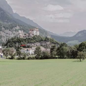 Maestosa vista della rocca di Gutenberg a Balzers, circondata da campi verdi e dalle imponenti Alpi.