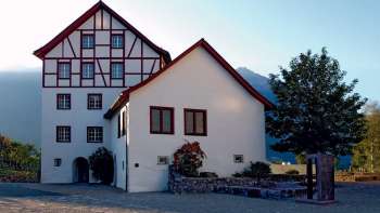 L'insieme degli edifici storici del Pfrundbauten con la facciata a graticcio e lo sfondo delle montagne del Liechtenstein nella luce della sera.
