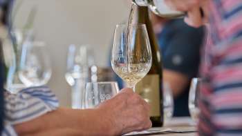 Un bicchiere di vino bianco viene versato durante una degustazione guidata.