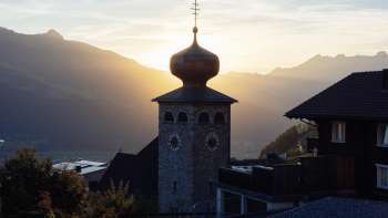 Cupola a cipolla della chiesa parrocchiale di San Giuseppe con il sole al tramonto sullo sfondo