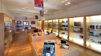 Vista su una luminosa sala espositiva del Museo Lawena con vetrine illuminate piene di apparecchi elettrici storici.