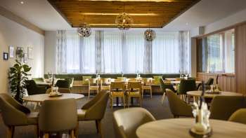 Un altro angolo della sala da pranzo, con gli stessi tavoli rotondi, un'atmosfera accogliente e moderne installazioni di illuminazione.