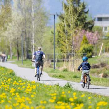 Pedalare in famiglia sulla pista ciclabile di primavera nel Parco Naturale di Haberfeld, circondati da prati e alberi in fiore.