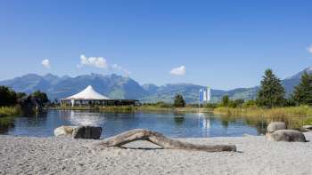 Area di balneazione naturale con sabbia, legni di scarto e vista sulle Alpi del Liechtenstein nell'Impianto ricreativo di Grossabünt.
