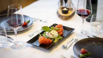 Un'altra vista della tavola imbandita, con particolare attenzione ai moderni piatti neri e alle stoviglie al centro.