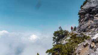 Escursionisti sullo stretto sentiero Fürstensteig in Liechtenstein con vista sulle nuvole sotto il sentiero