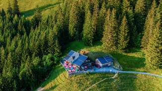 Vista aerea del rifugio Gafadurahütte su un pendio di montagna soleggiato, circondato da boschi e prati alpini nel Liechtenstein
