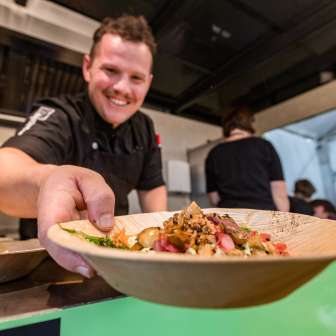 Lo chef serve un piatto di piatti regionali al Genussfestival di Vaduz, nel Liechtenstein - evento culinario incentrato sul divertimento