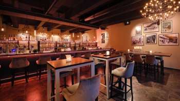 Interni eleganti del ristorante con elementi in legno scuro, area bar e sedie confortevoli in un ambiente accogliente.