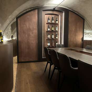 Elegante sala degustazione dell'WY Weinbar con soffitto a volta ed elegante tavolo in legno per esclusive degustazioni di vino.