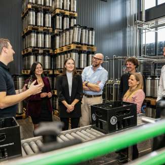 Gruppo di visitatori in visita guidata al birrificio del Liechtenstein con una panoramica della produzione