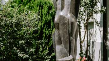 Scultura moderna in bronzo, in piedi tra fiori e cespugli a Vaduz - opera di Herbert Albrecht.