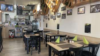 Interni accoglienti del ristorante con tavoli moderni in legno, tovaglioli verdi ed elementi decorativi