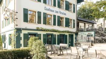 Terrazza invitante con tavoli e sedie in legno di fronte alla Gasthaus zum Hirschen