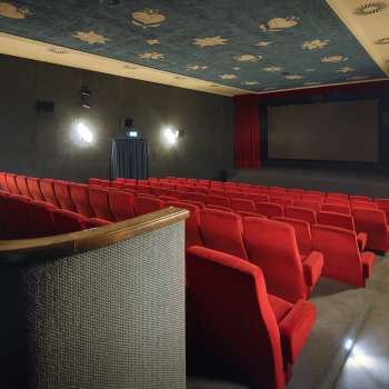 Vista laterale della sala cinematografica dell'Altes Kino Vaduz con poltrone rosse e illuminazione d'atmosfera.
