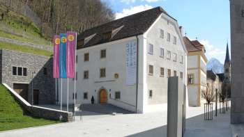 Vista del museo nazionale del Liechtenstein a Vaduz con edifici storici e bandiere colorate