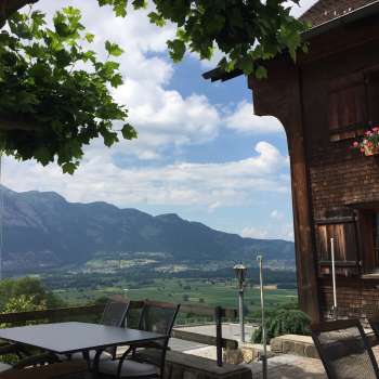 Edificio tradizionale con terrazza soleggiata e panorama montano sullo sfondo