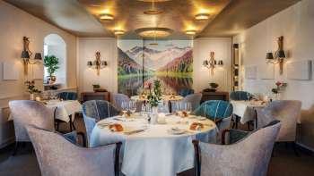 Elegante sala da pranzo con tavoli apparecchiati con stile, ambiente elegante e grande quadro paesaggistico