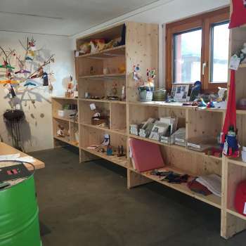 Interno della Birkahoflädile con scaffali in legno pieni di prodotti regionali, decorati con elementi colorati - negozio di fattoria in Liechtenstein.
