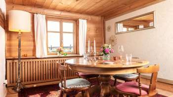 Accogliente sala da pranzo con rivestimenti in legno, tavolo da pranzo rotondo e interni rustici